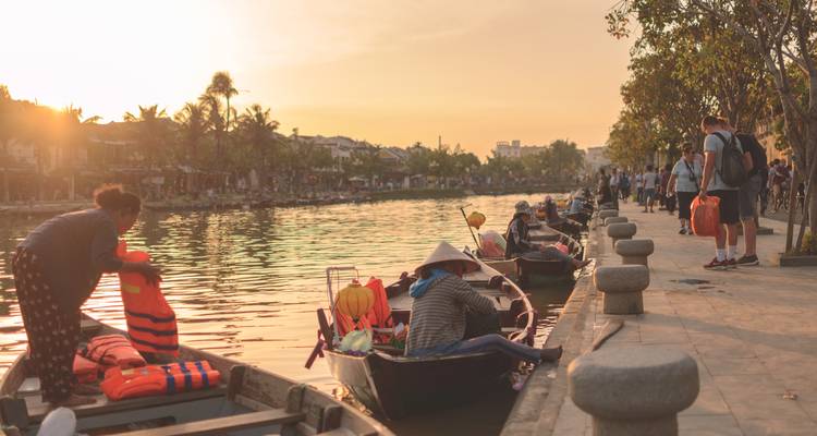 Menschen bereiten Boote am Flussufer bei Sonnenuntergang vor.