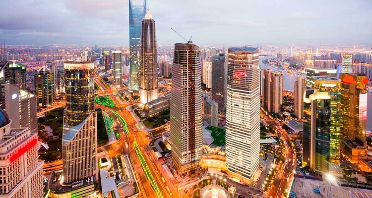 Vue aérienne crépusculaire des gratte-ciel illuminés de Shanghai et des routes surélevées animées.