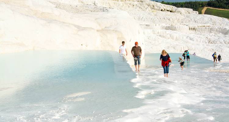Touristen, die auf Terrassen mit türkisfarbenem Wasser wandeln.