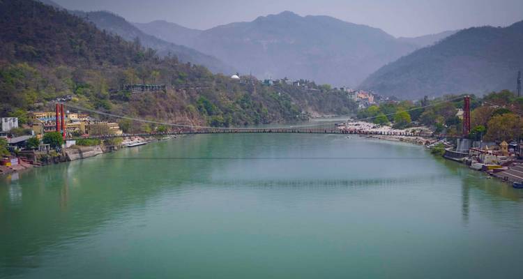 Pont suspendu au-dessus d'une rivière avec des collines.