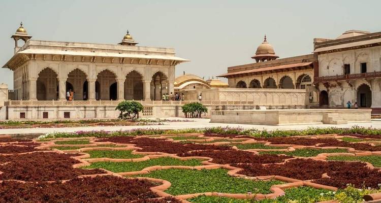 Binnenplaats van Agra Fort met decoratieve tuinen en historische zandstenen gebouwen.
