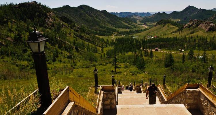 Escalier menant vers une vallée luxuriante et montagneuse.