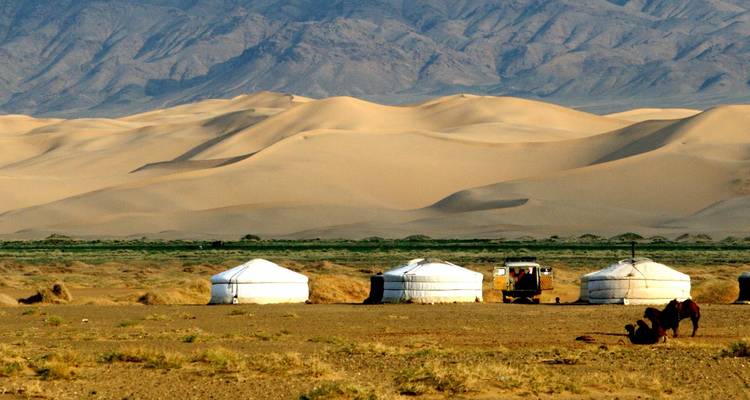 Yourtes mongoles traditionnelles avec des dunes de désert en arrière-plan.