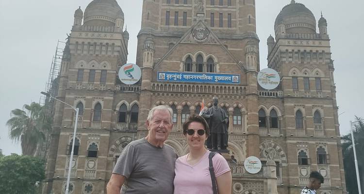 Two people posing in front of a historic building.