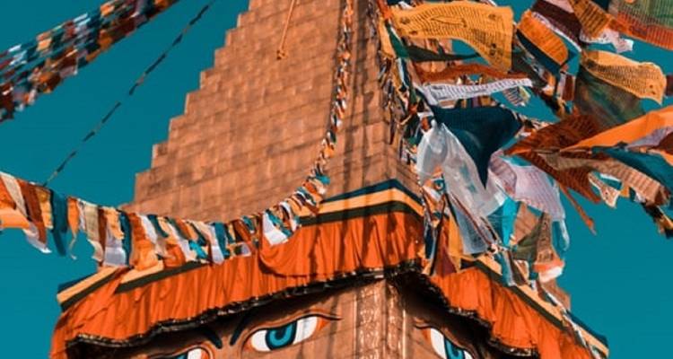 Temple spire with prayer flags against a blue sky.