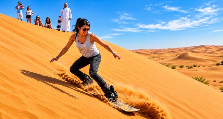 Una mujer bajando en sandboard por las dunas del desierto de color naranja brillante mientras sus amigos observan desde la cresta bajo un cielo azul profundo.