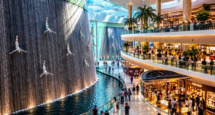 Interior del Dubai Mall con una espectacular cascada que cuenta con esculturas de buzos y una galería comercial de varios niveles.