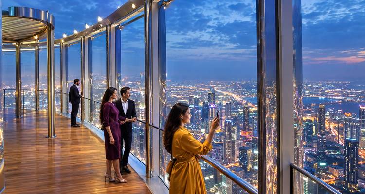 Les visiteurs sur une plate-forme d'observation en verre capturent des vues nocturnes scintillantes sur Dubaï