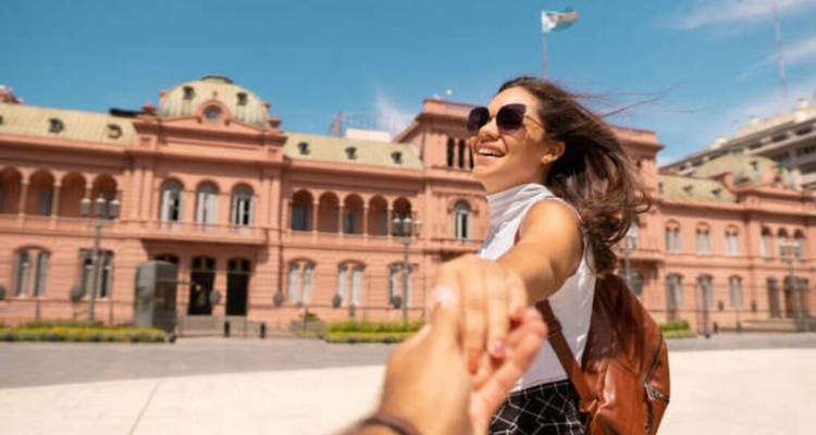 Woman holding hands with a person in front of a historic building.