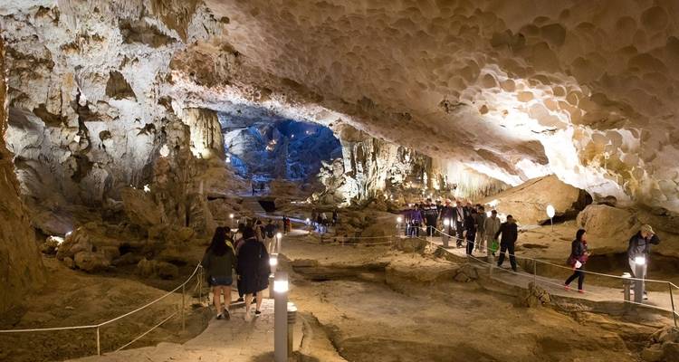 Visitors exploring a large cave with stalactites.