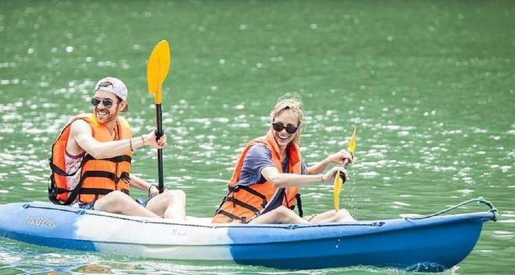 Two people kayaking on a green river.