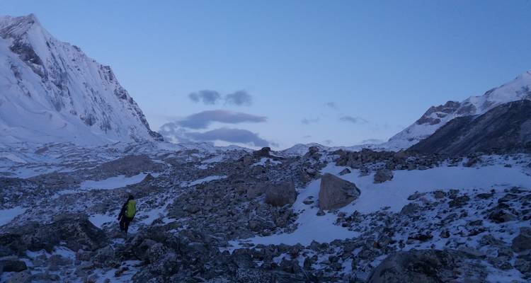 Een persoon die door een besneeuwde bergachtige omgeving loopt.