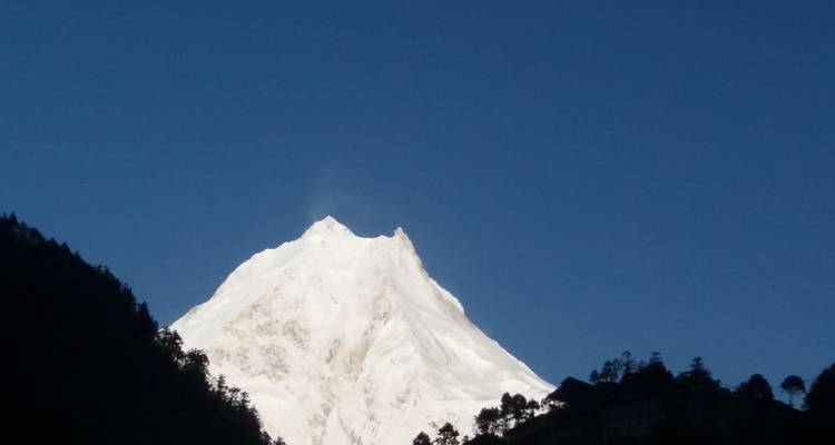 Besneeuwde bergtop tegen een helderblauwe lucht.