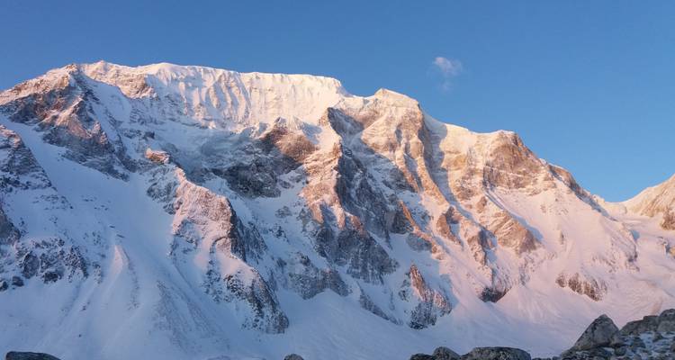 Besneeuwde berg met roze gloed tijdens zonsondergang.