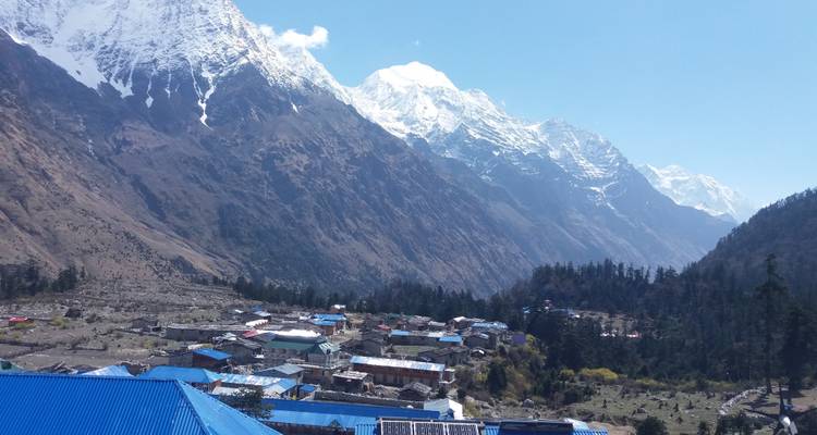 Bergdorp met blauwe daken en besneeuwde bergtoppen.