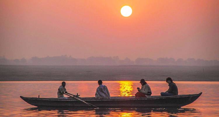 Personas en un barco con la puesta de sol de fondo.