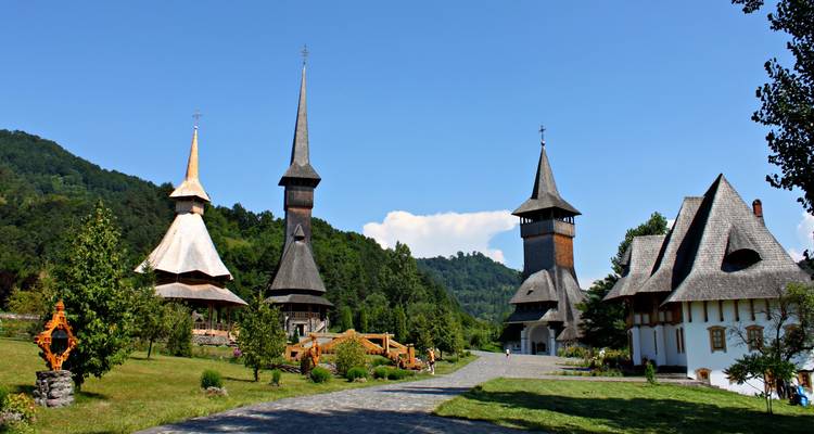 Ensemble de clochers d'église en bois élancés et fins dans une vallée verdoyante sous un ciel bleu