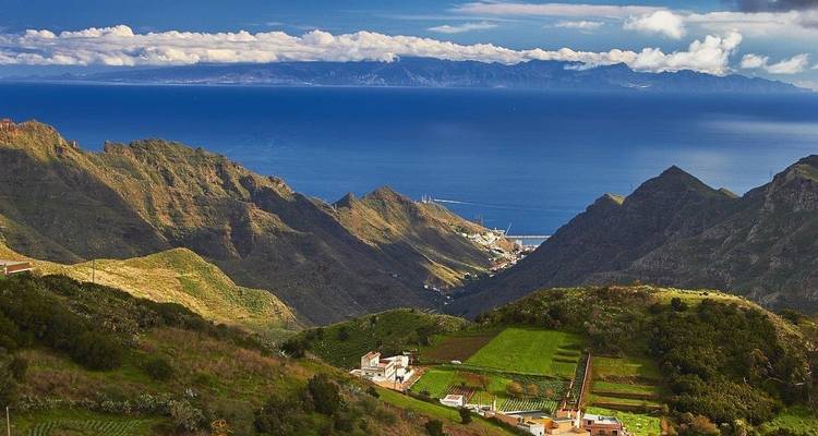 Panoramic view of a coastal landscape with mountains and the sea.
