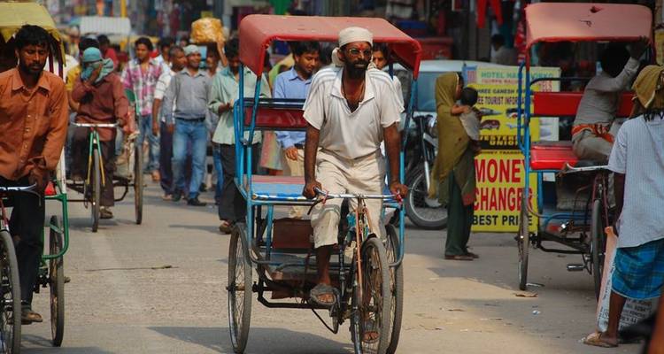 Eine belebte Straße mit Rikscha-Verkehr und Fußgängern.