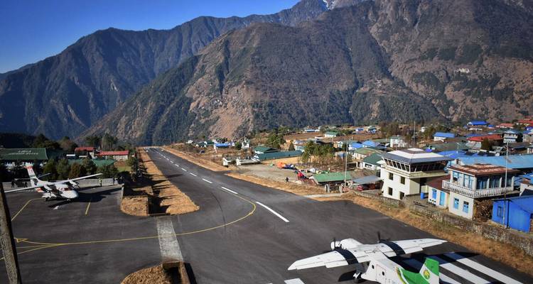 Kleiner Bergflugplatz in Lukla mit kurzer Landebahn, umgeben von steilen grünen Gipfeln.
