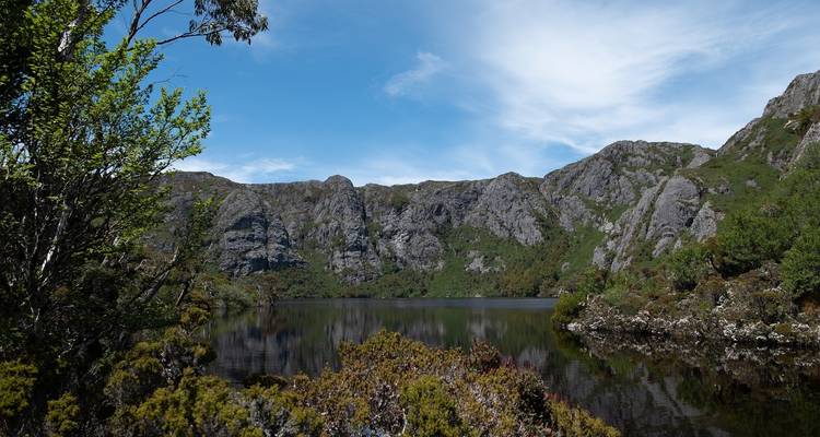 Ruhiger See mit Bergen im Hintergrund unter einem blauen Himmel.