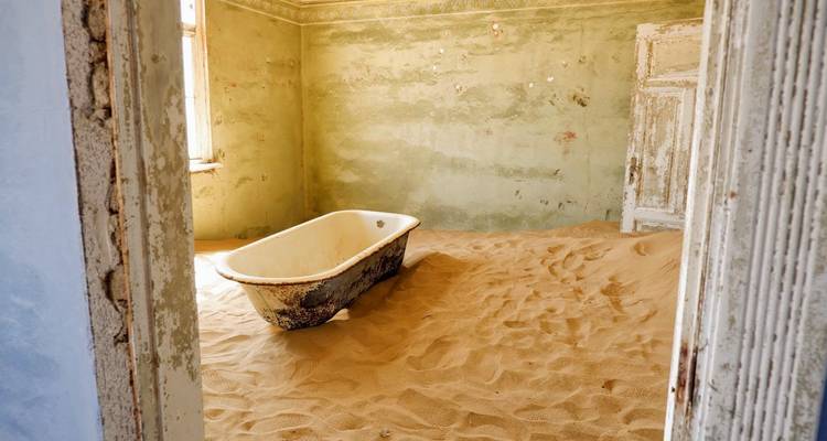Intérieur d'une pièce avec du sable recouvrant le sol et une baignoire.