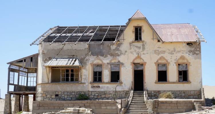 Bâtiment abandonné avec un toit cassé et une façade altérée par les intempéries.