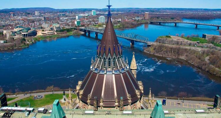 Vue aérienne de la tour du parlement aux toits de cuivre surplombant un large fleuve bleu et des ponts