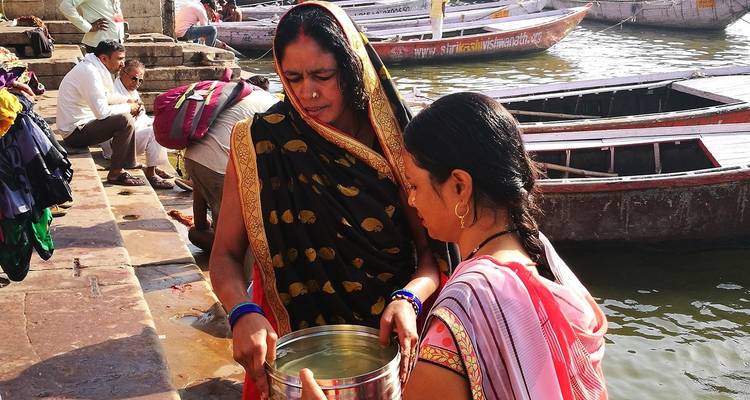 Twee vrouwen bij een rivier met boten op het water.
