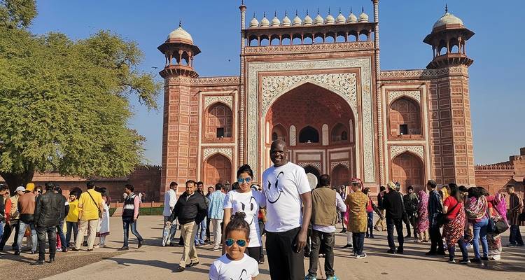 Familie poseert voor een grote roodstenen poort.
