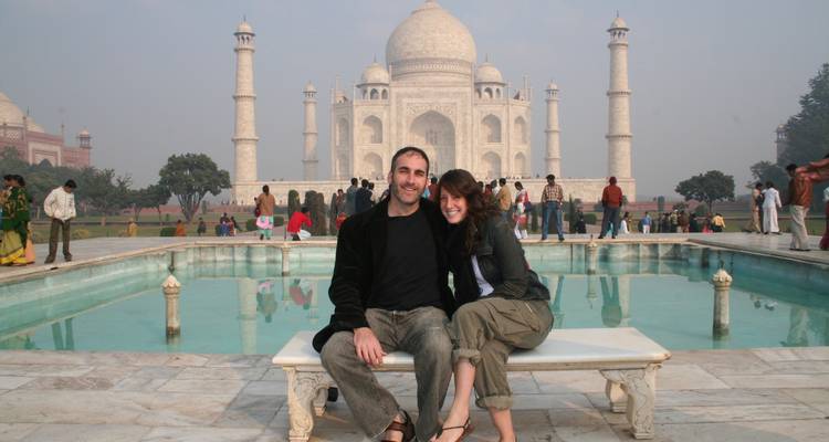 Paar sitzt vor dem Taj Mahal.