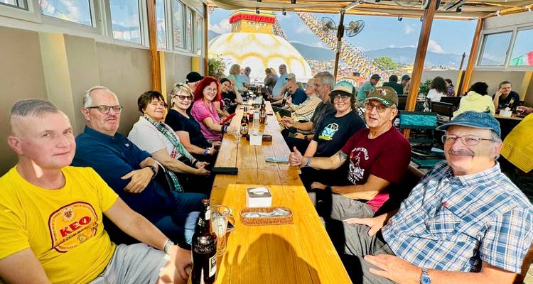 Groupe de touristes dînant en plein air avec des bouteilles de boisson sur la table.