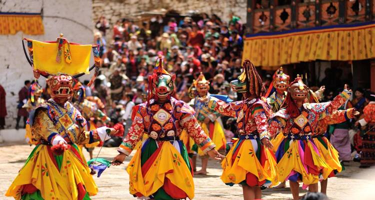 Danse traditionnelle bhoutanaise avec masques devant une foule.