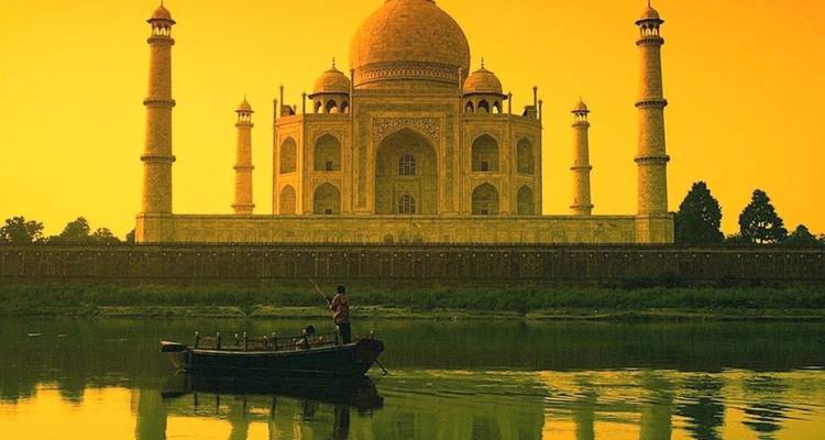 Im goldenen Licht erstrahlend erhebt sich das Taj Mahal jenseits des spiegelnden Yamuna-Flusses, wo ein einzelner Bootsführer bei Sonnenaufgang ruhig rudert.