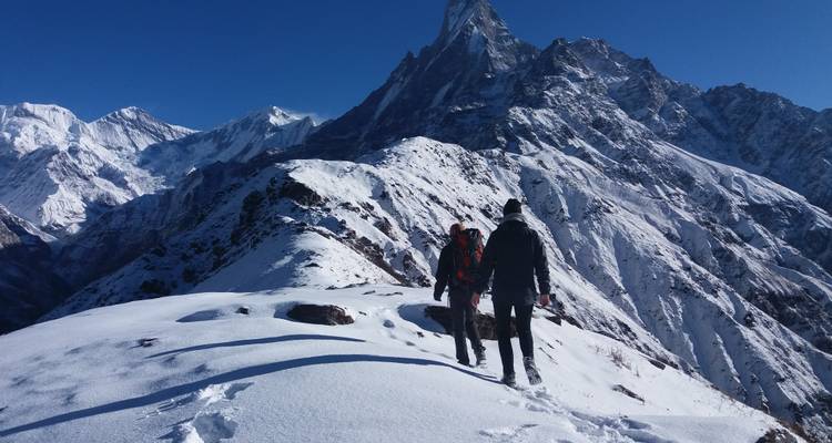 Zwei Wanderer, die auf Schnee gehen, mit einer atemberaubenden Bergaussicht.