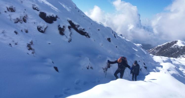 Zwei Personen, die einen verschneiten Hang mit verschneiter Landschaft besteigen.