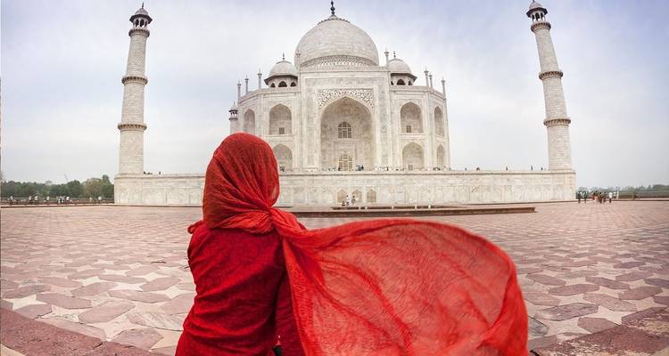 Eine Person in roter Kleidung, die das Taj Mahal betrachtet.