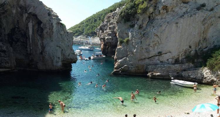 Mensen zwemmen en ontspannen in een rotsachtige baai.