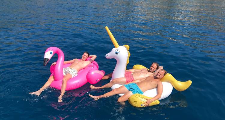 Mannen die luieren op opblaasbare drijvers in de zee.