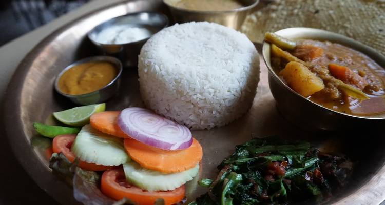 Een schotel met een traditionele maaltijd bestaande uit rijst, curry en groenten.