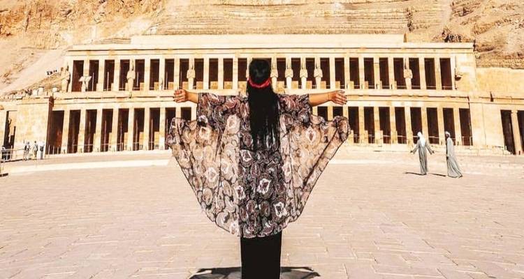 Person mit offenen Armen vor einer großartigen antiken Tempelfassade.