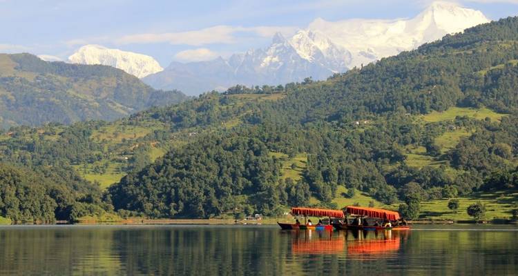 Holzboote auf einem ruhigen See mit Bergblick.