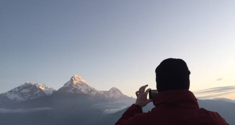 Personne photographiant un lever de soleil sur la montagne.