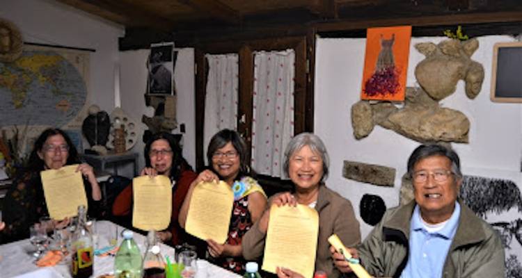 Een groep mensen die in een rustieke kamer zit en papieren vasthoudt.