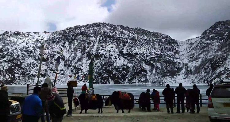 Een besneeuwde meer omringd door bergen met mensen op bezoek.