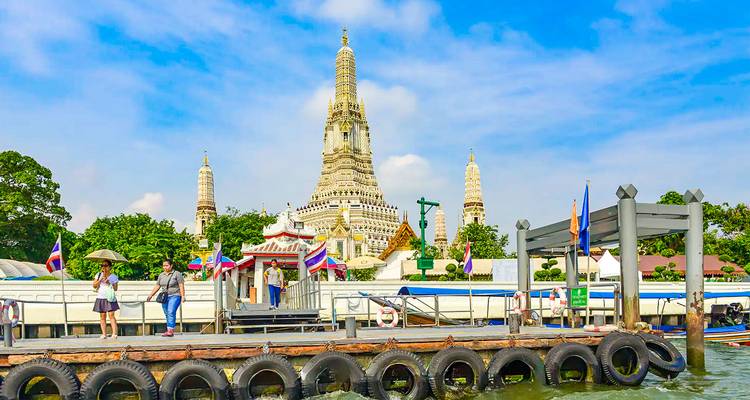 Iconic Wat Arun temple with a river view and a pier in the foreground.