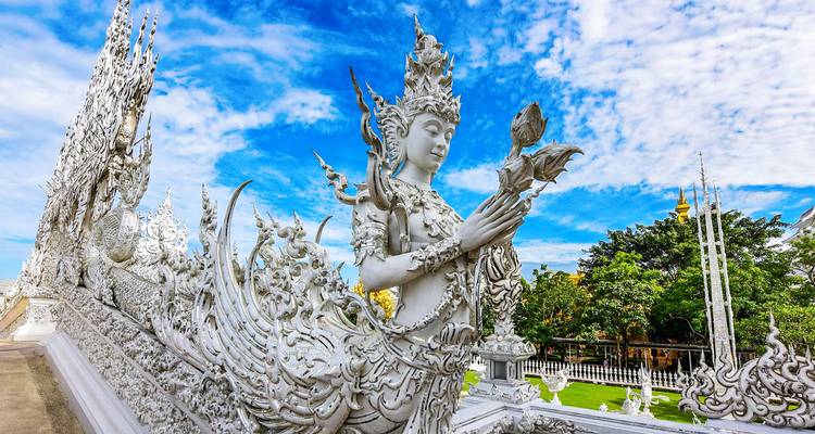 Intricately carved white temple statue with a blue sky backdrop.