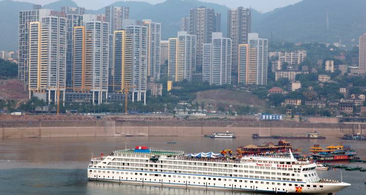 Kreuzfahrtschiff in einem Stadthafen mit Wolkenkratzer-Skyline.