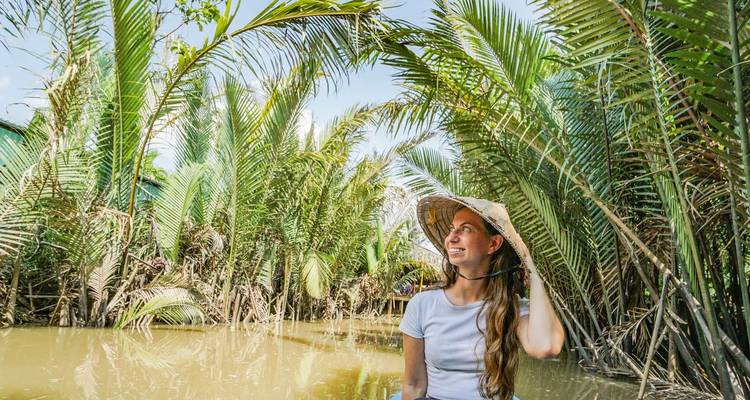 Femme souriante dans un bateau entourée de verdure de jungle