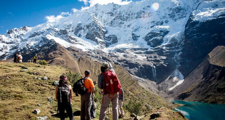 Trekker mit Blick auf eine ausgedehnte Gletscherlandschaft und den türkisfarbenen See unterhalb des Salkantay-Gipfels.
